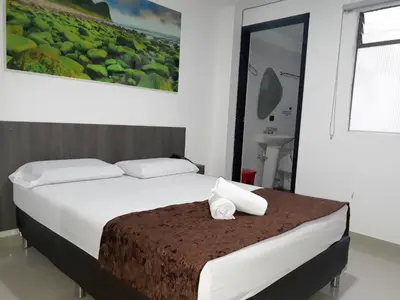 a bedroom with a bed with two pillows on it at Hotel Jardin de Laureles Jeps in Medellín