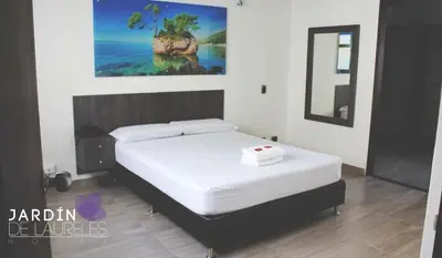 a bedroom with a white bed with a painting on the wall at Hotel Jardin de Laureles Jeps in Medellín
