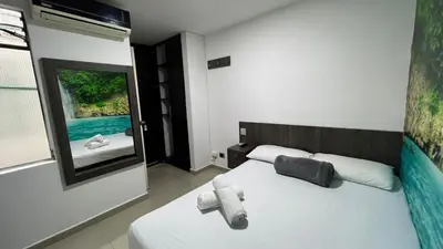 a bedroom with a white bed and a window at Hotel Jardin de Laureles Jeps in Medellín