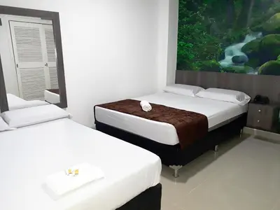 a room with two beds and a painting on the wall at Hotel Jardin de Laureles Jeps in Medellín