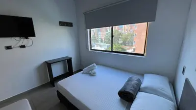 a small bedroom with a bed and a window at Hotel Jardin de Laureles Jeps in Medellín