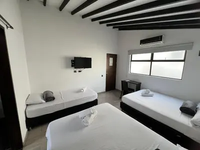 a room with two beds and a flat screen tv at Hotel Jardin de Laureles Jeps in Medellín