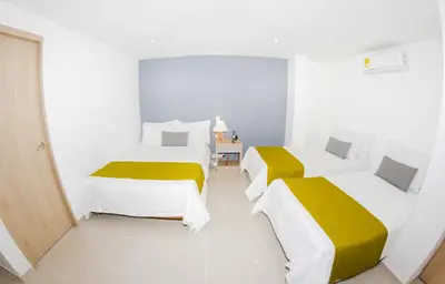 two beds in a white room with yellow and white sheets at Hotel Boutique Laureles Medellin (HBL) in Medellín