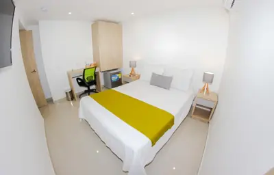 a bedroom with a large bed with a yellow blanket at Hotel Boutique Laureles Medellin (HBL) in Medellín