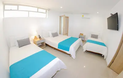 a bedroom with two beds and a flat screen tv at Hotel Boutique Laureles Medellin (HBL) in Medellín
