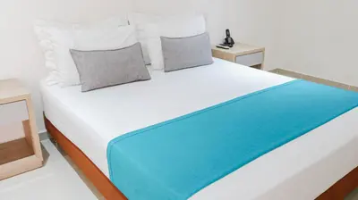 a large white bed with a blue blanket on it at Hotel Boutique Laureles Medellin (HBL) in Medellín