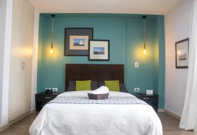 a bedroom with a large bed with a blue wall at Apartahotel Millennials in Manizales