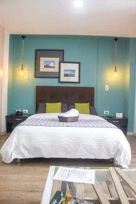a bedroom with a large bed with blue walls at Apartahotel Millennials in Manizales