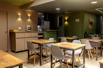 a restaurant with wooden tables and white chairs at Poblado Guest House in Medellín