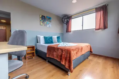 a bedroom with a bed and a desk and a window at Poblado Guest House in Medellín