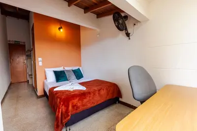 a small bedroom with a bed and a chair at Poblado Guest House in Medellín