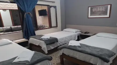 a room with three beds and a window at Hotel Caldas Plaza in Caldas