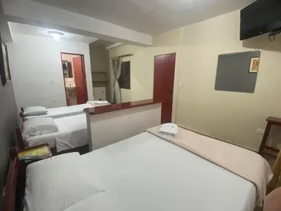 a hotel room with two beds and a mirror at Hotel Caldas Plaza in Caldas