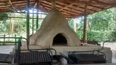 an outdoor oven with two benches under a roof at Alojamiento rural el Refugio en santagueda in Santagueda