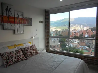 a bedroom with a bed and a large window at San Peter Suites in Medellín