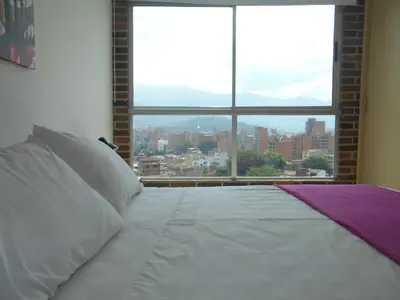 a bed in a room with a large window at San Peter Suites in Medellín