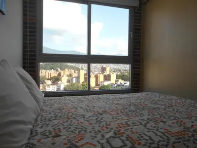 a bedroom with a view of a city from a window at San Peter Suites in Medellín
