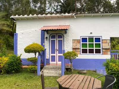 a blue and white house with a purple door at Cabañas y Flores in Jericó