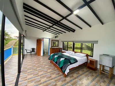 a bedroom with a bed and a balcony at Cabañas y Flores in Jericó