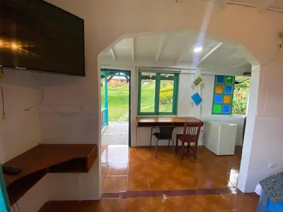 a room with a table and chairs and a tv at Cabañas y Flores in Jericó