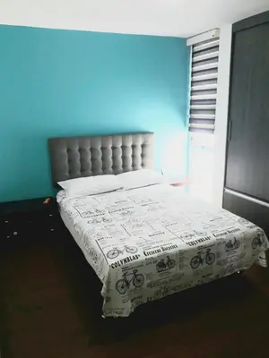 a bed in a bedroom with a blue wall at Apartamento En Sabaneta in Sabaneta