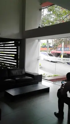 a living room with a black couch and a large window at Apartamento En Sabaneta in Sabaneta