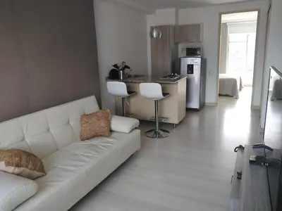 a living room with a white couch and a kitchen at San Peter Apartments in Medellín