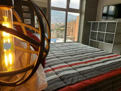 a bedroom with a bed with a view of a city at San Peter Apartments in Medellín