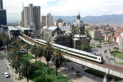 a train is crossing a bridge over a city at San Peter Apartments in Medellín