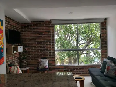 a living room with a brick wall and a large window at San Peter Family Suites in Medellín
