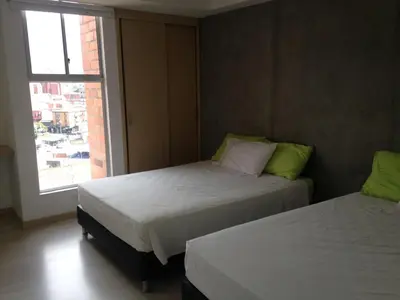 two beds in a room with a window at San Peter Family Suites in Medellín