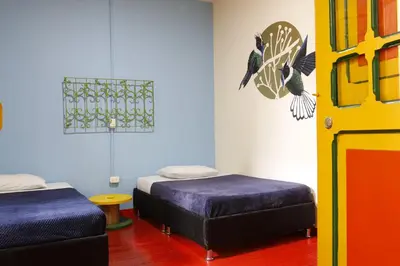 a room with two beds and a door with birds on the wall at Golden Frog Manizales in Manizales