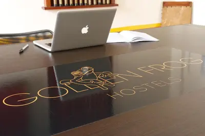 a book on a table with a laptop on it at Golden Frog Manizales in Manizales