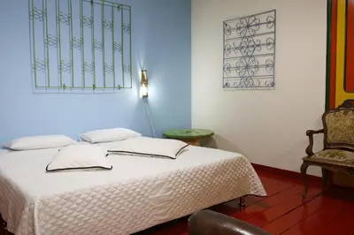 a bedroom with a white bed and a chair at Golden Frog Manizales in Manizales
