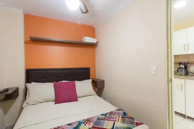 a bedroom with a bed with an orange wall at Apartamentos Laureles de la 70 in Medellín