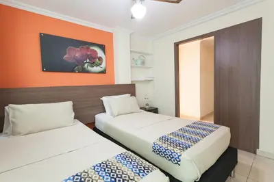 two beds in a room with an orange wall at Apartamentos Laureles de la 70 in Medellín