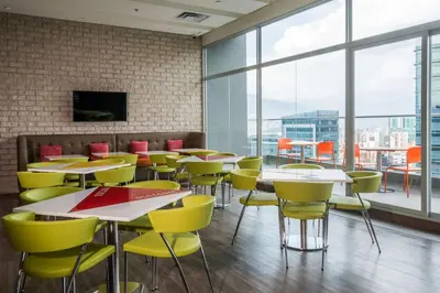 a dining room with tables and yellow chairs at Hampton by Hilton Medellin in Medellín