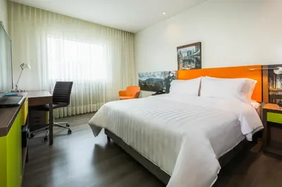 a hotel room with a large bed and a desk at Hampton by Hilton Medellin in Medellín