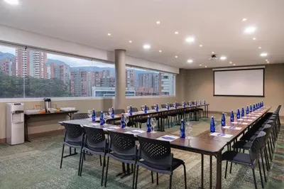 a conference room with long tables and chairs and a screen at Hampton by Hilton Medellin in Medellín