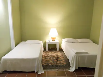 two beds in a room with a lamp on a table at Casamarilla in Mariquita