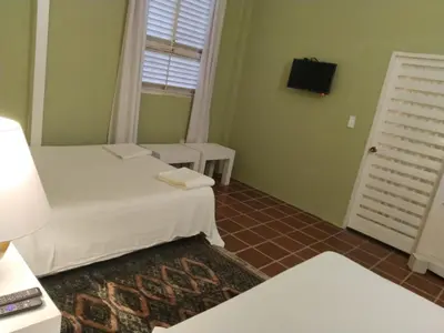 a room with two beds and a window and a television at Casamarilla in Mariquita