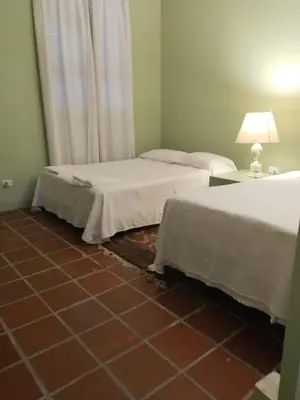two beds in a room with a tiled floor at Casamarilla in Mariquita