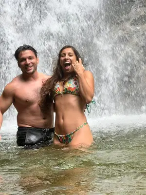 a man and woman standing in the water in front of a waterfall at Yolo Hostel Medellin in Medellín