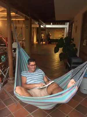 a man sitting in a hammock reading a book at Yolo Hostel Medellin in Medellín