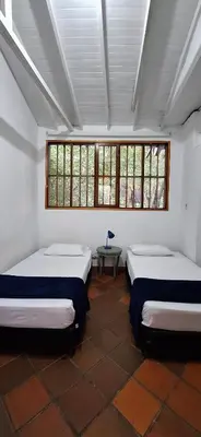 a room with two beds and a table and windows at Yolo Hostel Medellin in Medellín