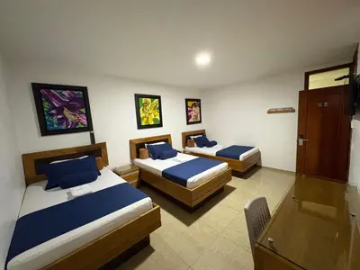 a hotel room with two beds with blue pillows at Hotel Monarca in Medellín