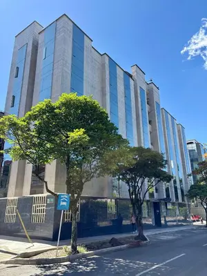 a tall building with trees in front of a street at Hotel Monarca in Medellín