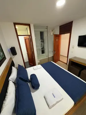 a hotel room with a large bed with blue pillows at Hotel Monarca in Medellín