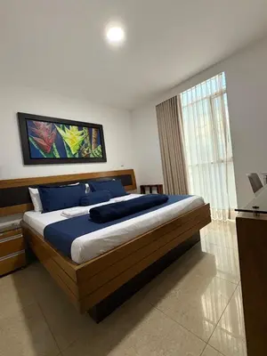 a bedroom with a bed with blue pillows and a window at Hotel Monarca in Medellín