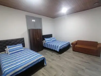 a room with two beds and a chair in it at ANGIE`s HOUSE in Manizales